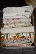 A box of vintage table cloths and embroidered place mats