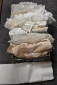 A box of vintage table cloths and linen some being lace worked.