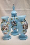 An early 20th century mantel garniture set of two vase and an urn in blue custard glass decorated
