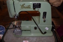 A vintage mid century Cresta sewing machine, in green with peddle, power cable and original case