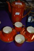A Crown Devon lustrous orange four setting coffee set, with coffee pot.