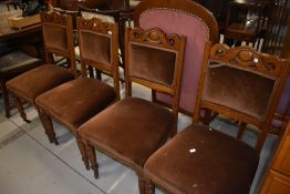 A set of four early 20th century oak framed dining chairs having turned legs and carved oak backs