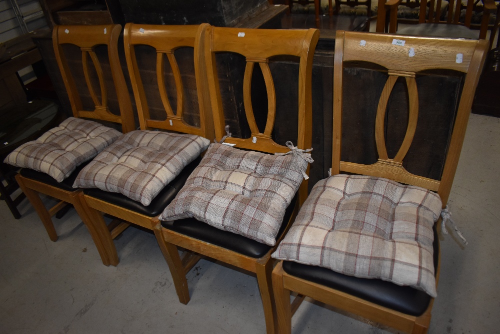 A set of four modern oak dining chairs having leatherette seats and check cushions