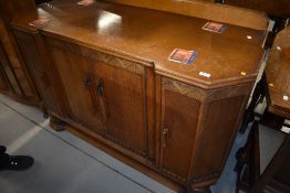 An early 20th Century golden oak sideboard having shaped front and turned deco style handles