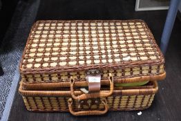 A traditional picnic basket housing a collection of plastic plates and bowl.