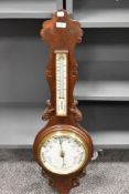 An early 20th century aneroid banjo barometer, with carved details and bevelled glass face in