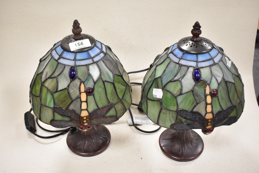A pair of Tiffany style table lamps having dragon fly decoration to green and blue glass shade.