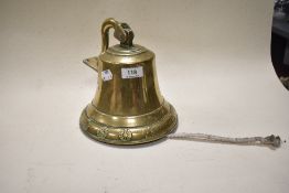 A vintage brass wall mounted bell having embossed floral pattern to base.