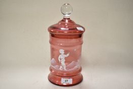 A Cranberry glass lidded jar having white enamelled decoration in the style of Mary Gregory.