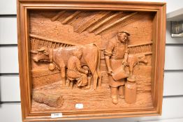 A deeply carved vintage soft wood plaque, having scene of couple milking cows in barn, signed C A
