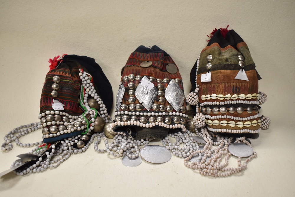 Three vintage Thai mountain tribe hats, having coin, bead and shell decoration.