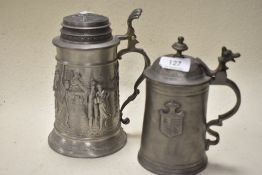 Two vintage steins, one having hunting scene, the other a coat of arms.
