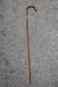 An antique textured wood walking cane having silver cuff to shaft and silver pips to handle.