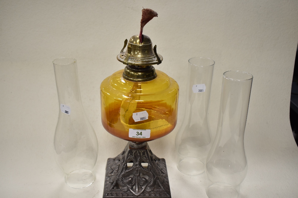 A late 19th/early 20th century oil lamp, having cast metal base with anchor design, amber glass