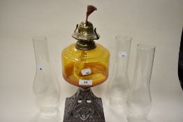 A late 19th/early 20th century oil lamp, having cast metal base with anchor design, amber glass