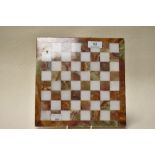 An onyx chess board, interspersed with white natural stone squares, having polished finish.