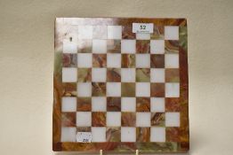 An onyx chess board, interspersed with white natural stone squares, having polished finish.