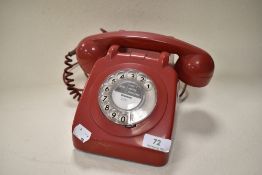 An iconic 1960s red rotary telephone.