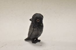 A cast metal owl having hinged head and glass eyes.