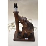 A Mid century Burmese carved lamp having elephant with his trunk wrapped around a tree trunk.