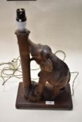 A Mid century Burmese carved lamp having elephant with his trunk wrapped around a tree trunk.