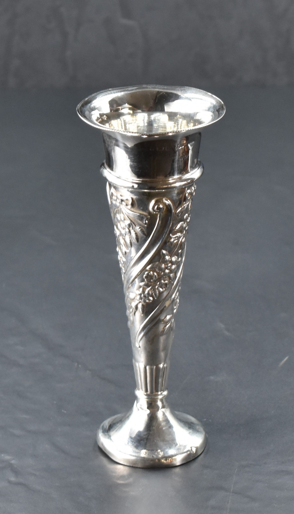 A late Victorian silver spill vase, of tapering cylindrical or trumpet form, embossed with foliate