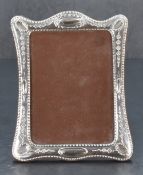 A modern white metal-mounted photograph frame, of traditional design with embossed decoration and