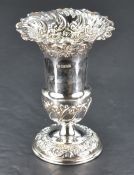 A late Victorian silver vase, of urn-form with flared rim, decorated with embossed C-scrolls,
