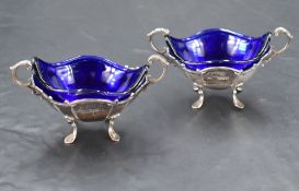 A pair of late Victorian silver salts, of fluted oval form with scrolled rim, handles and feet,
