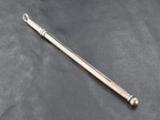 An early 20th century silver propelling cocktail swizzle stick, engine-turned with sliding action,