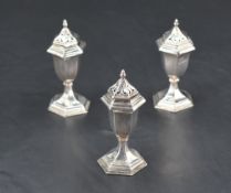 A group of three silver pepperettes, of hexagonal form with pierced finial topped pull-off covers,
