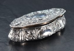 An Edwardian silver dressing table or jewellery box, of shaped oval form embossed throughout with