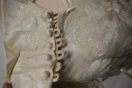 A late 1950s cream wedding dress and veil, dress having full length sleeves with buttons to cuffs