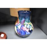 An early 20th century Moorcroft pottery vase in the Orchid pattern on blue ground with blue