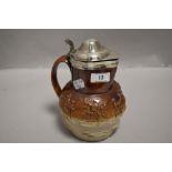 An antique Doulton style stone ware hunting scene jug having HM silver rim and lid.