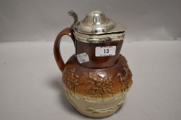 An antique Doulton style stone ware hunting scene jug having HM silver rim and lid.