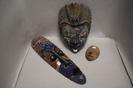 Two modern hand decorated Indonesian face masks with a similar painted African mask