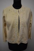 A 1950s/60s cream wool cardigan having heavily beaded decoration and lined in silk, having Wong