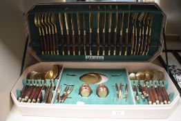 A Housley International canteen of cutlery in brass with teak handles.