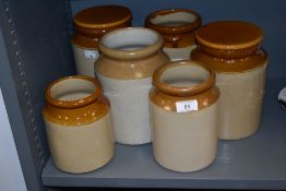Six vintage salt glazed earthen ware kitchen storage jars, two having lids.