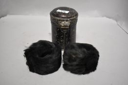 A pair of antique fur cuffs in a vintage tin.