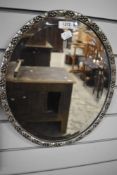 A modern moulded oval wall mirror in silver tone 40cmx33cm approx.