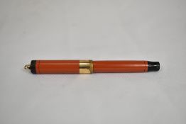 A Parker Duofold button fill fountain pen in coral red with broad ring to the cap and ringtop having