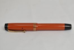 A Parker Duofold Jr Lucky Curve button fill fountain pen in coral red with two bands to cap having