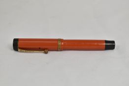 A Parker Duofold Jr Lucky Curve button fill fountain pen in coral red with single band to cap having