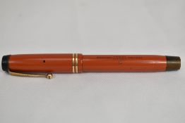 A Parker Streamlined Junior Duofold button fill fountain pen in coral red with two rings to the