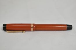A Parker Duofold button fill fountain pen in coral red with two bands to cap having Parker Duofold