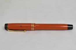 A Parker Duofold Special button fill fountain pen in coral red with two bands to cap bearing the