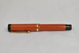 A Parker Duofold Jr Lucky Curve button fill fountain pen in coral red with single band to cap having