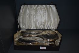 A case containing a selection of HM silver dressing table items, most damaged